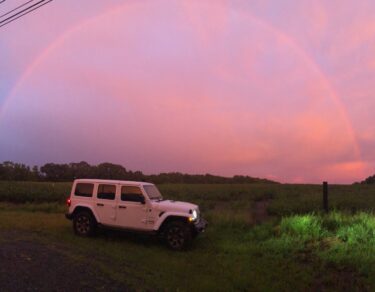 White Jeep underneath a full rainbow